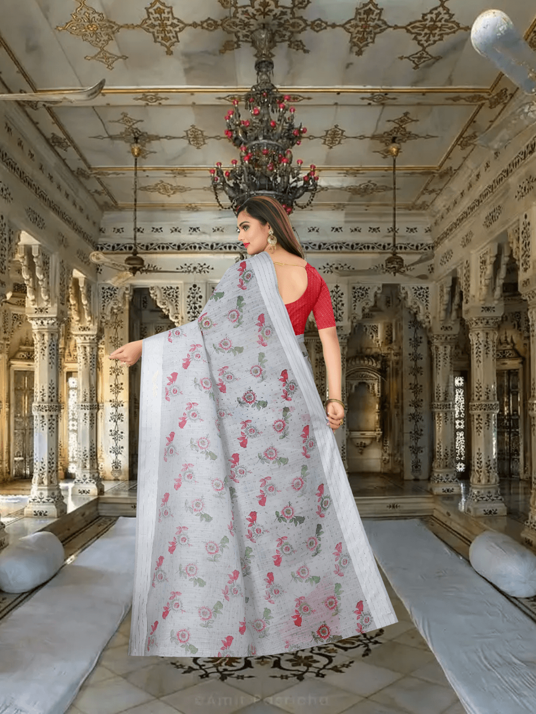 Model holding the pallu in classic pose under warm palace room lighting