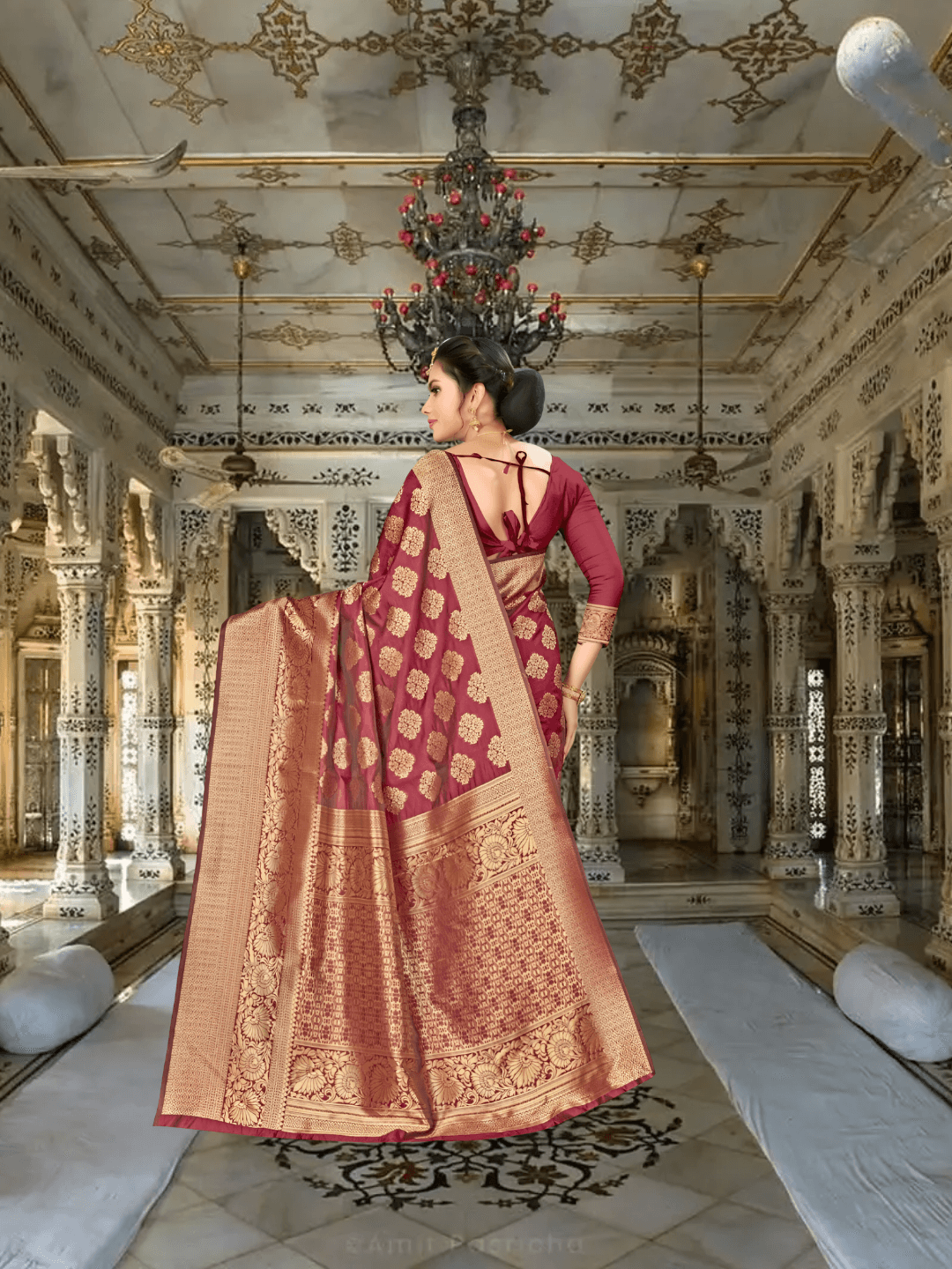 Extended pallu of maroon saree with intricate gold work displayed in regal interior