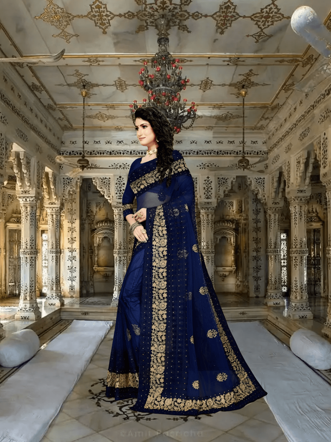 Model in navy net saree under royal chandelier glow, borders gleaming with threadwork