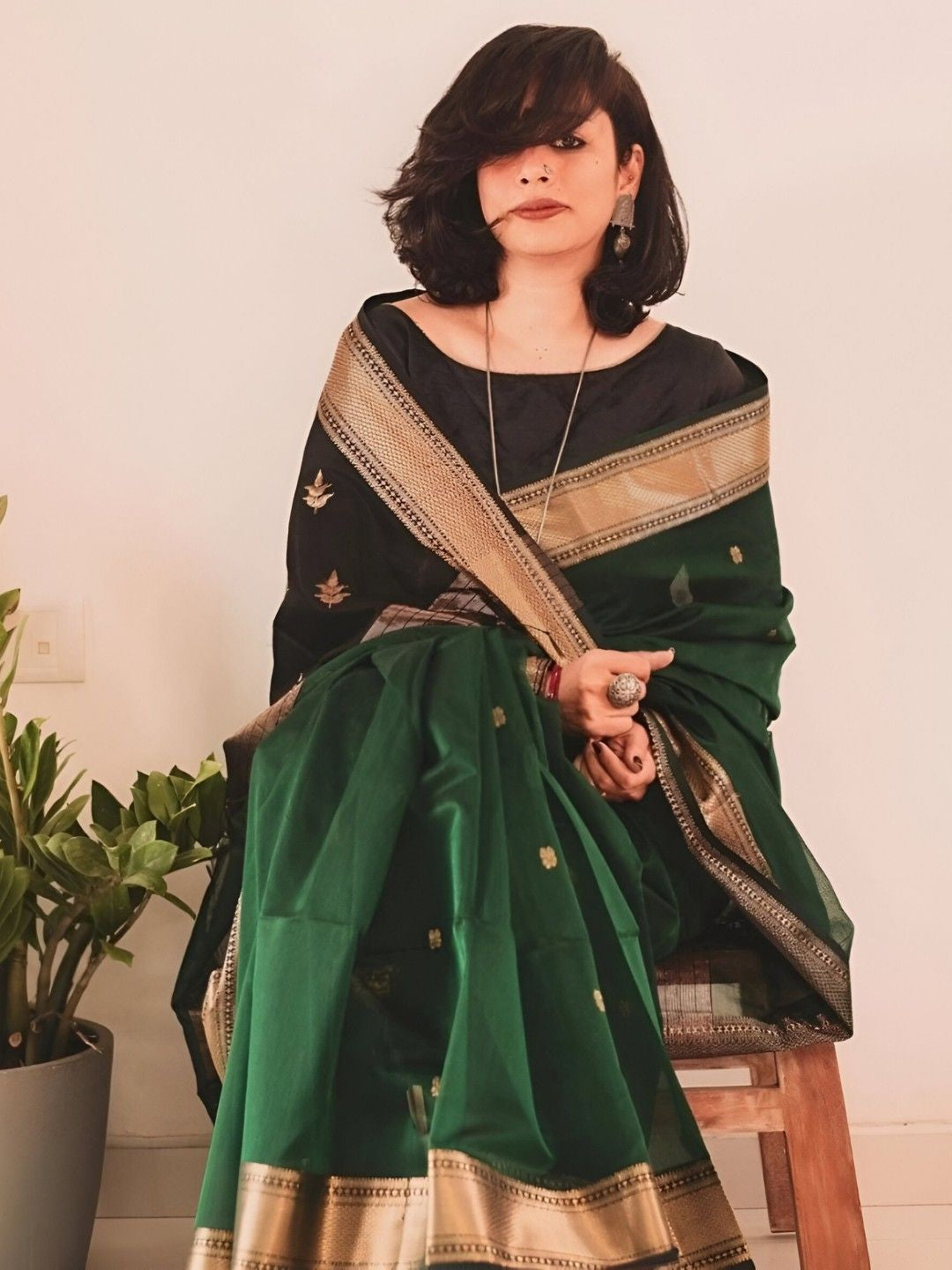 Model seated, hand resting on vintage chair