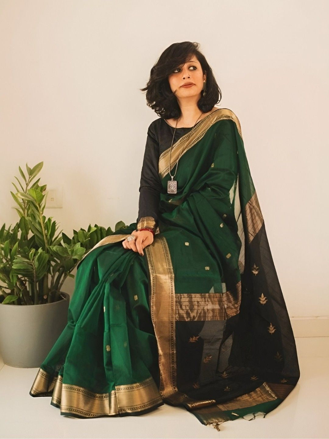 Model seated, hand resting on vintage chair