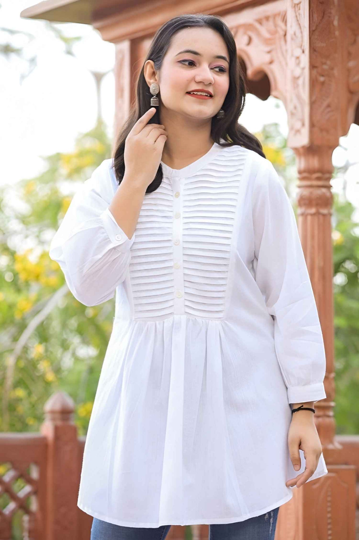 Front view of white tunic against stone chapel walls, fabric cascading like frozen breath in winter light