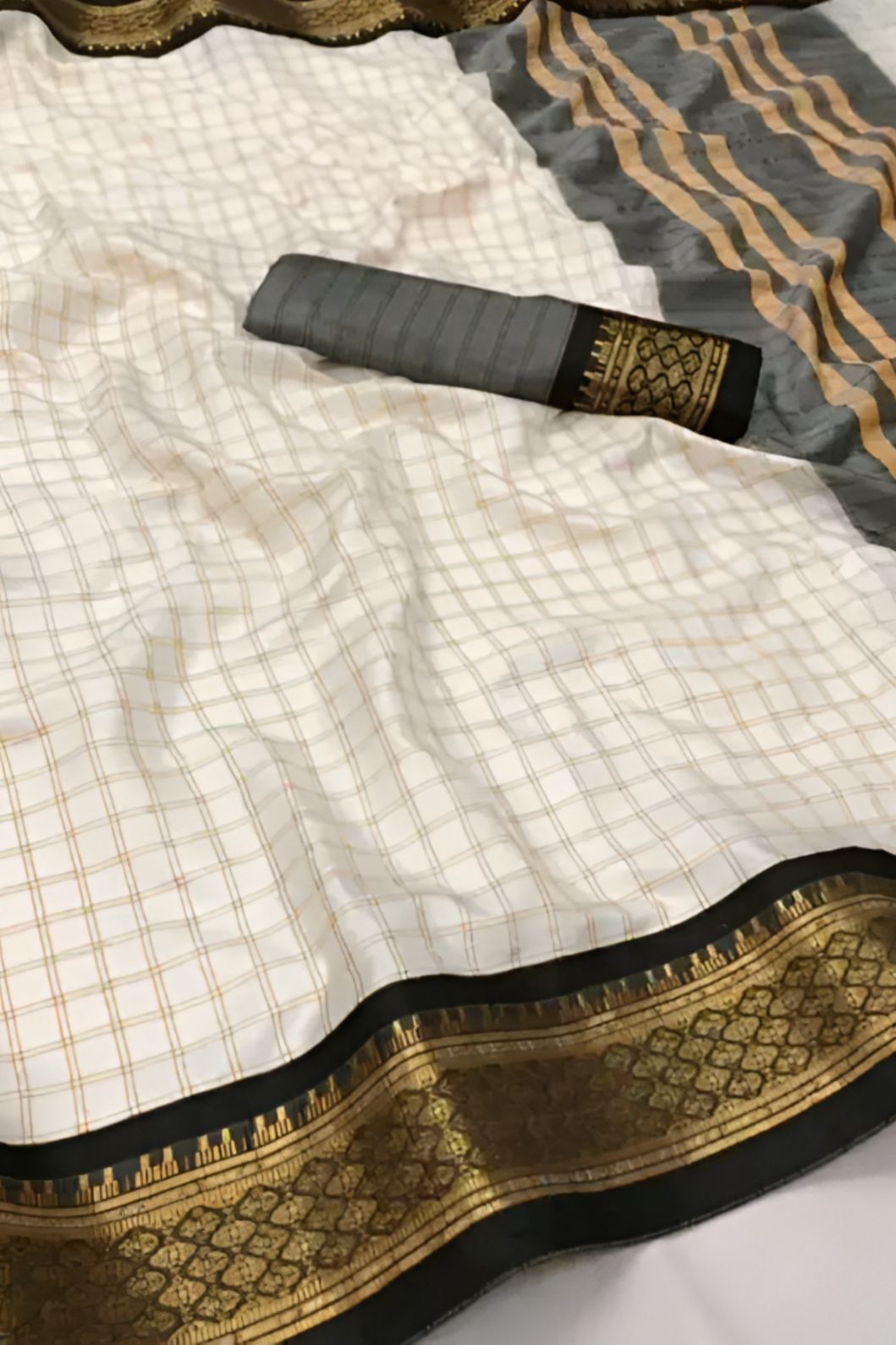 Studio close-up of black-gold border detail on soft white saree