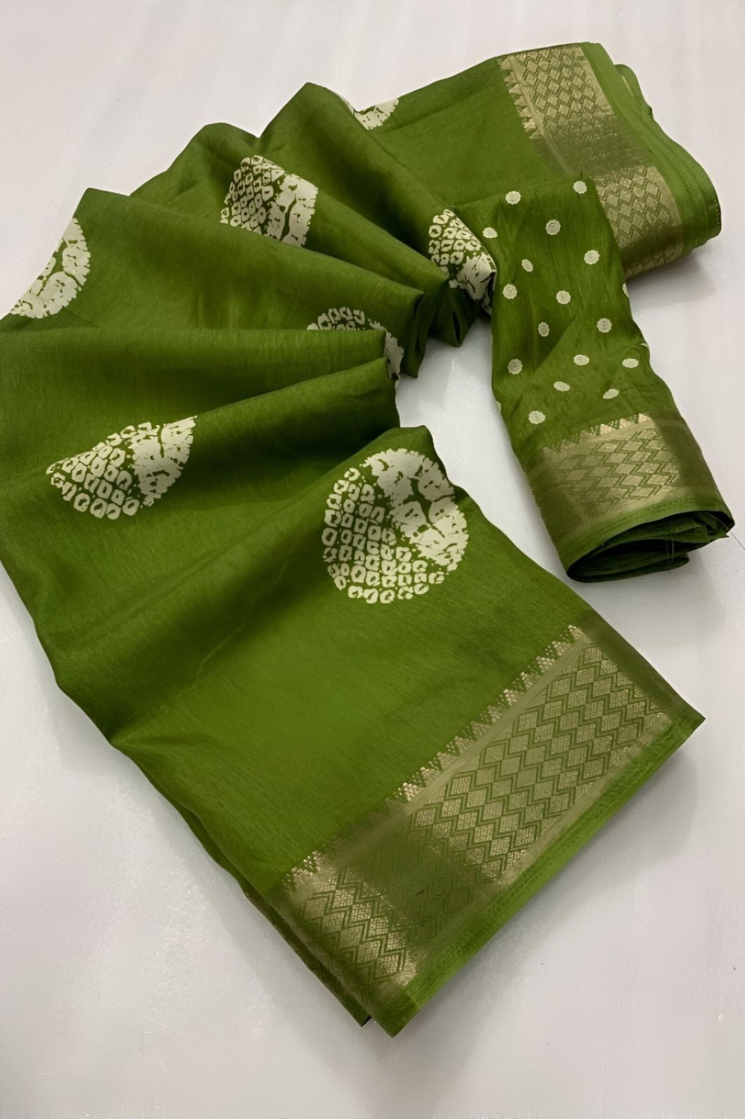 Closeup of green cotton crape fabric print, border, and thread detail