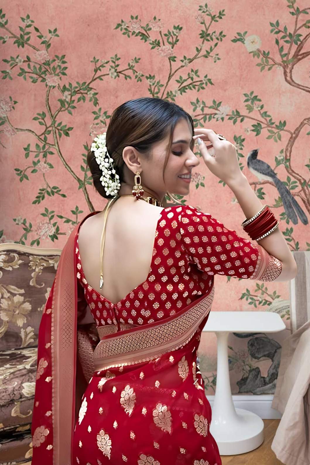 Back profile showcasing bold red pallu in ceremonial lighting