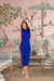 Model wearing blue sleeveless dress with ribbon – confident front view