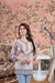 Front view of multicolor kurti against crumbling mural, sleeves catching confetti
