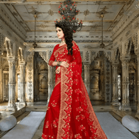 Bride in red net saree descending palace stairs, gold zardozi blazing under chandeliers