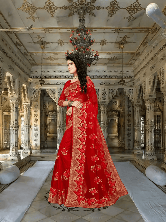 Bride in red net saree descending palace stairs, gold zardozi blazing under chandeliers