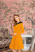 Front view of Golden Contrast knit dress in yellow with black collar/shoulder accents, styled on a model against a neutral background.