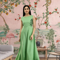 Front view of sleeveless green full-length crepe gown in palace setting
