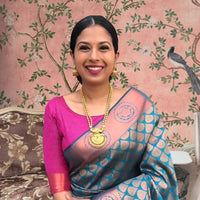 Front view of blue-green printed Litchi silk saree with pink blouse in palace setting