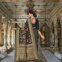 Black saree with gold zari pallu flowing in royal interior backdrop