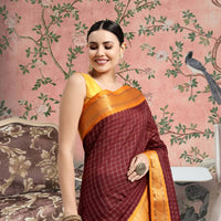 Woman draped in coffee-colored saree standing gracefully