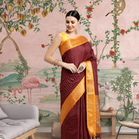 Woman draped in coffee-colored saree standing gracefully