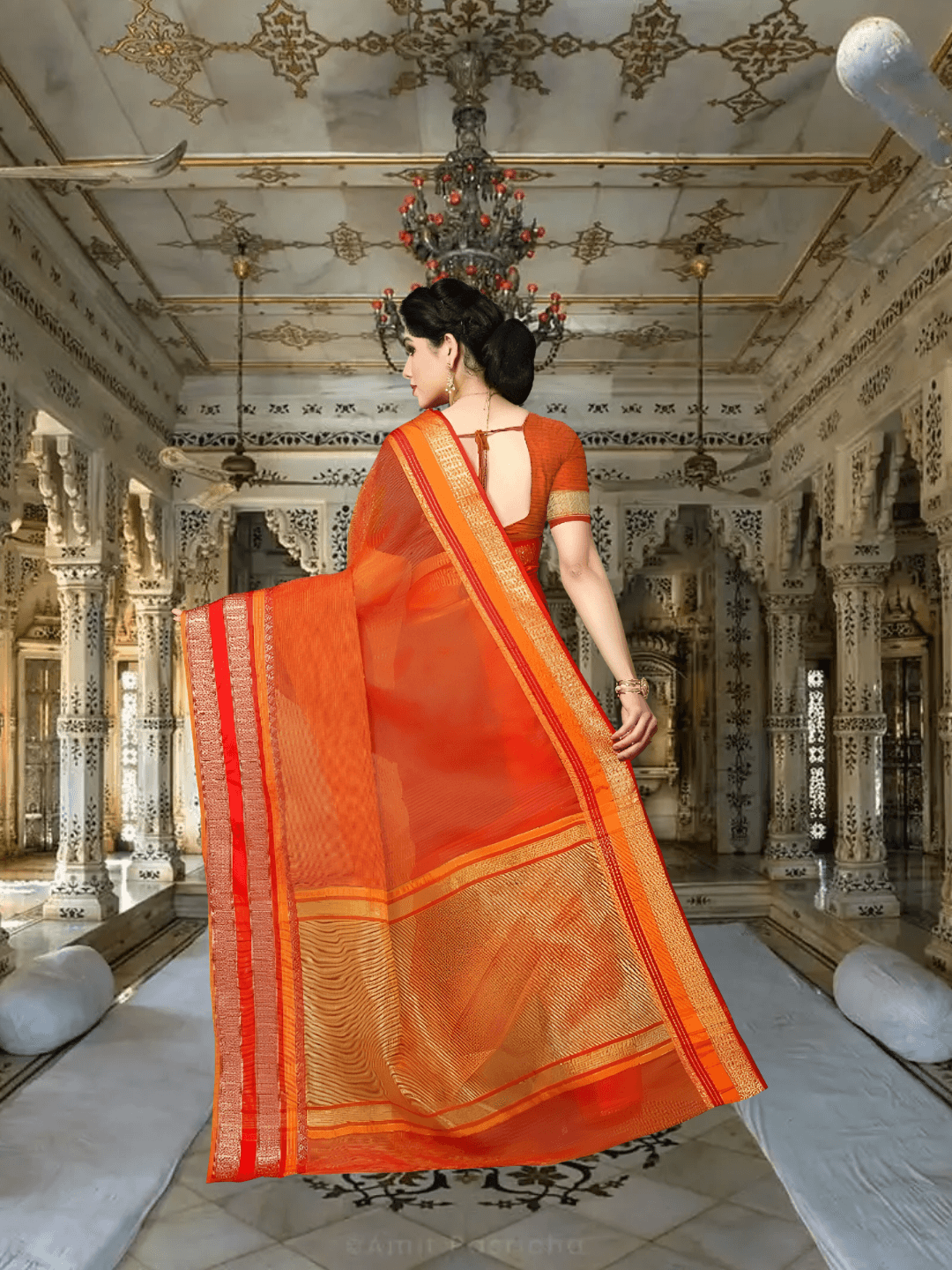 Model in orange saree with golden borders, standing gracefully