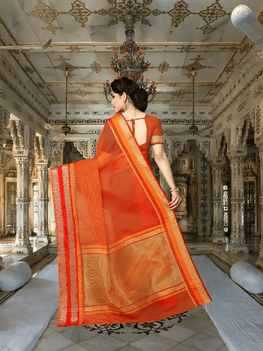 Model in orange saree with golden borders, standing gracefully