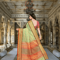 Model gracefully standing in light green saree inside heritage-style room