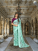 Model in light pista green cotton saree with floral prints, standing in regal palace room