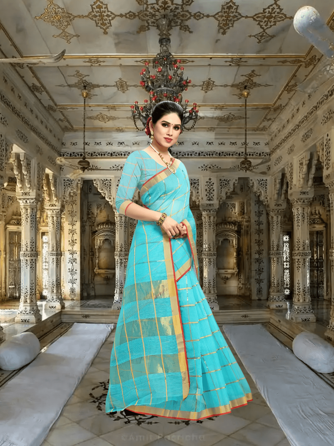 Model turned sideways in sky blue checkered saree under warm palace lighting