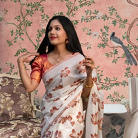  Front view of white-orange silk saree in a floral-themed palace backdrop