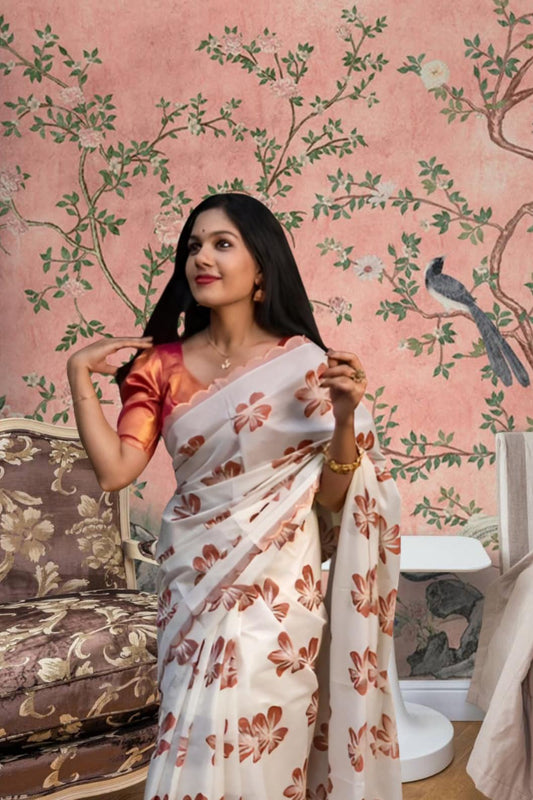  Front view of white-orange silk saree in a floral-themed palace backdrop