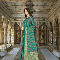 Model in green Banarasi saree with pink floral motifs in palace backdrop