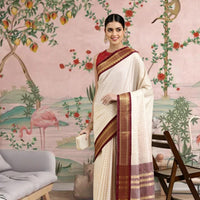 Front view of white checkered cotton silk saree with maroon border in regal setting
