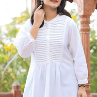  Front view of white tunic against stone chapel walls, fabric cascading like frozen breath in winter light