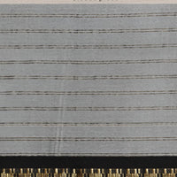 Studio close-up of black-gold bordered blouse detail on soft white saree