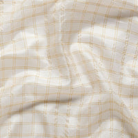 Studio close-up of black-gold border detail on soft white saree