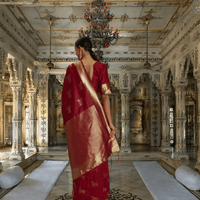 Red silk saree with gold elephant motifs and ornate border shown in royal setting
