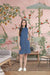  Front view of sleeveless denim dress against brick wall