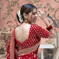 Back profile showcasing bold red pallu in ceremonial lighting
